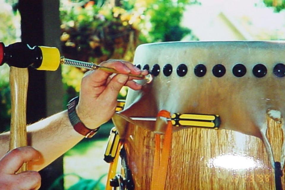 Close up of someone tacking a newly stretched drum head